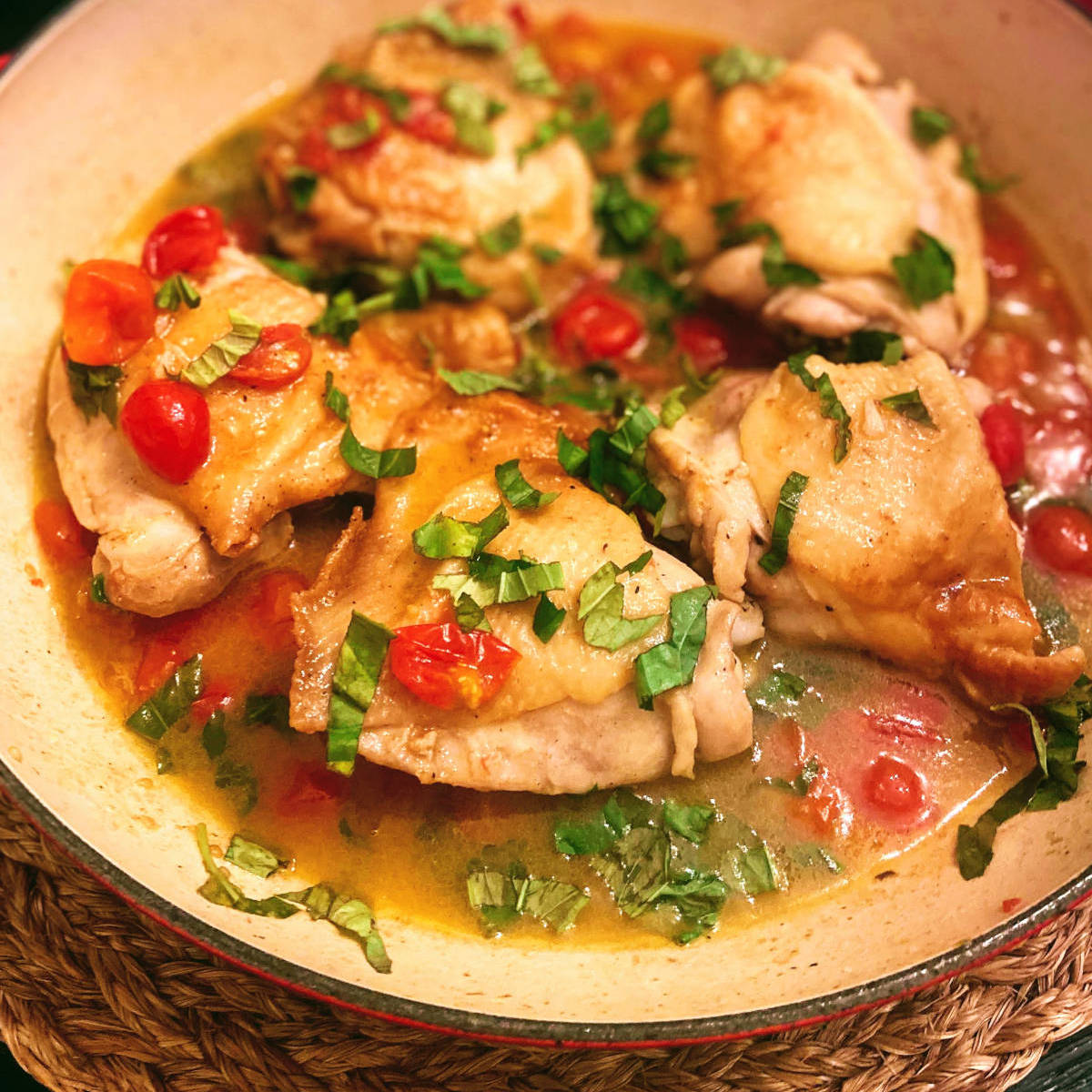 chicken thighs in pan with cherry tomatoes and basil